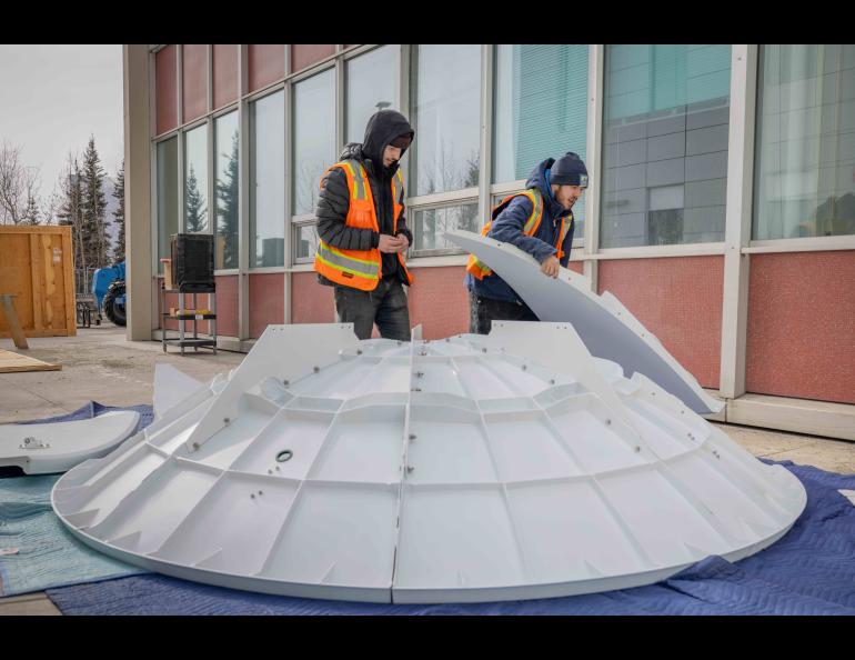 University of Alaska Fairbanks Facilities Services employees Mckinley Hearns, left, and Shae Patterson assemble the reflector dish of the new Geographic Information Network of Alaska antenna on Wednesday, April 3, 2024. Photo by Bryan Whitten