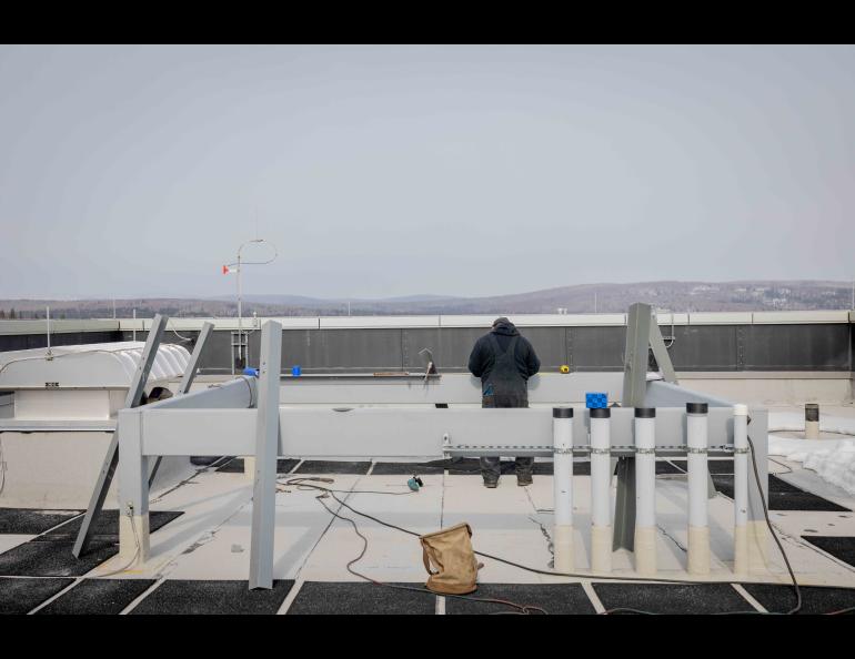 A worker with the installation contractor prepares the UAF Usibelli Building rooftop site for the new Geographic Information Network of Alaska antenna on Wednesday, April 3, 2024. Photo by Bryan Whitten